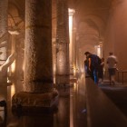 A sculpture depicting a hand emerges from a column in the Basilica Cistern of Istanbul, amidst water reflections, ancient legends, and a submerged atmosphere.