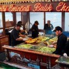 A fishing boat restaurant in the Eminönü market in Istanbul offers the famous balik ekmek, a sandwich with freshly grilled fish, served directly from the sea in a lively and authentic atmosphere.