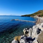 The turquoise waters of Mazı Bay are clear and perfect for swimming. The rugged coastline features small sandy and pebbly beaches nestled in lush vegetation.