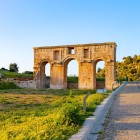 The ancient entrance of Patara, with its imposing Roman monumental arch, welcomes visitors among historic ruins and Mediterranean landscapes, bearing witness to the grandeur of ancient Lycia.
