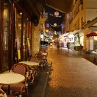 Rue Mouffetard at night, one of the oldest cobblestone Parisian streets, late at night with a fruit market and a coffee shop still open.