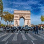 The Arc de Triomphe rises majestically over the Champs-Élysées, framed by trees and elegant buildings that enhance its perspective and symbolic presence in the heart of Paris.
