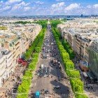 The Champs-Élysées stretch as a grand tree-lined avenue, framed by Belle Époque buildings and elegant boutiques, with historic monuments rising in the distance.