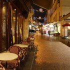 Rue Mouffetard at night, one of the oldest cobblestone Parisian streets, late at night with a fruit market and a coffee shop still open.
