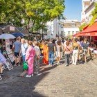 Tourists at the picturesque Place du Tertre: among colorful easels, they stop for a portrait or a caricature, sip coffee on lively terraces, immersed in the vibrant atmosphere.