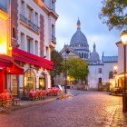 In the morning, Place du Tertre in Montmartre comes alive with café tables and artists setting up their canvases, as the Sacré-Cœur Basilica dominates the Parisian skyline.