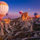 Hot air balloons soar over Cappadocia at sunset, offering spectacular views of lunar landscapes, fairy chimneys, and the magical colors of the sky.