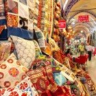 Fabrics, cushions, carpets, kilims, and scarves in vibrant colors at Istanbul’s Grand Bazaar, where art and culture intertwine in unique creations.