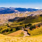 Picturesque Andean scenery in Ecuador, between Zumbahua Canyon and Quilotoa Lagoon, where a dirt road winds through cultivated fields and mountain landscapes.