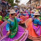 In Pujilí, Ecuador, indigenous women in colorful attire dance through the streets during a festival rich in colors and tradition.