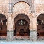 The arches of the Medersa in Fès display geometric carvings and refined arabesques, symbolizing 14th-century Islamic art and craftsmanship.