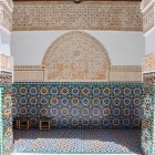 The portico around the courtyard of the Ben Youssef Madrasa is decorated with geometric zellige mosaics, wood carvings, and stucco, symbolizing Andalusian art and local craftsmanship.