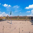 The façade of the National Palace stands at the center of Mexico City’s Zócalo, while on the left rises a Cathedral tower, symbol of history and identity.