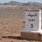 At the entrance of Alnif, there is a marker indicating access to the town, set among desert valleys and surrounded by rocky landscapes typical of southern Morocco.