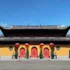 The Jade Buddha Temple features ochre-yellow walls and curved roofs, reflecting traditional Chinese architecture within a modern urban setting.