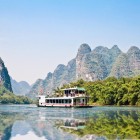 Cruise on the clear waters of the Li River in Guilin, among karst mountains and traditional villages reflecting the local history and nature.