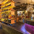 Elegant wine bar at Ramada Istanbul Pera, featuring warm lighting and wooden shelves for a unique and refined tasting experience.