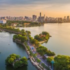 Panoramic view of Hanoi at sunset: West Lake reflects the golden sky, with the Tran Quoc Temple and the modern skyline creating a harmonious contrast.