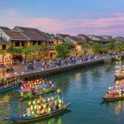 In the evening, boats on Hoi An’s river glide slowly among colorful lanterns, reflections on the water, and the charm of the historic Vietnamese town.