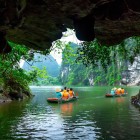 Exploring the Tam Cốc caves means discovering water tunnels between limestone mountains and the reflections of green landscapes on the tranquil waters.
