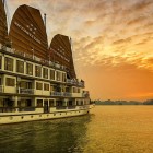 The Victory Star Cruise sails in Halong Bay at sunset, with golden waters and karst islets standing out against the fiery sky.