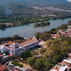 Chiapa de Corzo seen from above reveals its charming colonial center overlooking the Grijalva River, with red-tiled roofs, lush greenery, and boats lining the banks of Chiapas.