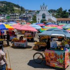 In the market of San Cristóbal de Las Casas, colorful umbrellas shade Indigenous vendors selling handmade goods and local foods, creating a lively mosaic of culture, tradition and color.