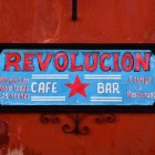 The vibrant sign of Restaurant Revolución stands out against the colonial red walls, inviting guests to a lively spot with a café bar, lounge, and live music every night in the heart of San Cristóbal.
