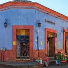 Maya street vendors in front of the colorful façade of a colonial shop in the city of San Cristóbal, Mexico.