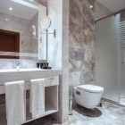 Modern and elegant bathroom with glass shower, marble-effect finishes, spacious sink and illuminated mirror. Bright, refined and comfortable space.