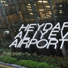 Baku Airport features a futuristic, organic style with large glass walls, curved volumes and wooden interiors recalling natural capsules, blending technology with elegant design.