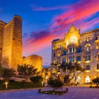 The Old City of Baku at sunset enchants with illuminated medieval walls and elegant buildings, blending ancient history and modern charm in the heart of Icherisheher.