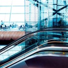 Modern interiors of Baku Airport with large glass walls, elegant escalators and a futuristic design. Bright spaces and curved lines create a refined, contemporary atmosphere.