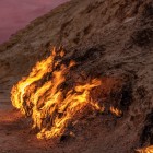 The Fire Mountain of Yanardag in Azerbaijan shows natural flames burning along the rocky slope, fueled by underground gas in a striking sunset setting.