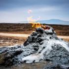 Mud volcano in Gobustan National Park, Azerbaijan, with natural gas emissions feeding small flames in a striking and unique geological landscape.