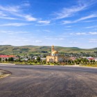 The photo shows the mosque of Mereze, Azerbaijan, with a golden dome at the village center, surrounded by houses and green hills in an authentic rural setting.