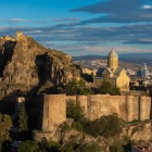 The bastions of Narikala Fortress rise on the rocky hill with imposing walls and ancient towers, overlooking Tbilisi with timeless charm.