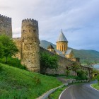 The road leading to Ananuri Fortress winds through green hills and reaches medieval towers and stone churches overlooking the scenic Lake Zhinvali in the heart of Georgia.