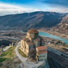 Aerial view of the Jvari Monastery overlooking Mtskheta, where the Kura and Aragvi rivers meet, surrounded by the Caucasus mountains and breathtaking Georgian landscapes.