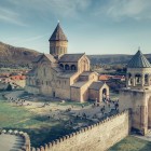 Aerial view of Svetitskhoveli Cathedral in Mtskheta, a masterpiece of medieval Georgian architecture, surrounded by ancient walls and the hills of the Mtkvari River valley.