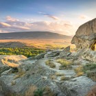 The rock-hewn city of Uplistsikhe, an ancient settlement carved into the rock in Georgia, overlooks the valley with millennia-old caves and stunning Caucasus landscapes.
