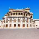 The Aram Khachaturian Opera and Ballet Theatre in Yerevan, an elegant architectural masterpiece and cultural symbol of the Armenian capital, under a bright blue sky.