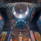 Interior of Khor Virap Monastery with stone vaults and a central dome on a drum, clean lines and soft light creating a spiritual atmosphere.