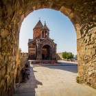 View of Khor Virap Monastery through a stone arch, with harmonious lines and typical details illuminated by Armenia’s warm light.