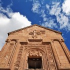 Facade of Noravank Monastery, Armenia: intricate carvings and stone crosses adorn the entrance, showcasing Armenian medieval art and spiritual heritage.