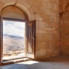 View from Noravank Monastery churches, Armenia: carved doorway opening onto Vayots Dzor canyon mountains, with natural light and breathtaking landscapes.