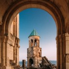 Finely carved stone arch frames the bell tower of Bagrati Cathedral. Harmonious lines and medieval details highlight the elegance of Georgian architecture.