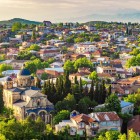 Beautiful morning view of Kutaisi’s historic center in Georgia, with the Catholic cathedral in the foreground, surrounded by green trees and mountains in the background.