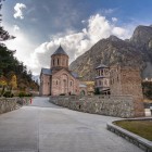 Monastery in the Dariali Gorge: an elegant stone complex set among the imposing Caucasus mountains, where sacred architecture and wild nature create an evocative atmosphere.