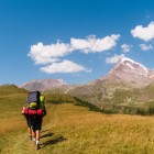Scenic trail through golden meadows and rolling hills, with the majestic Mount Kazbek in the background. A trek immersed in the wild nature of the Georgian Caucasus.